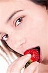 The face of a beautiful woman eating strawberries, isolated on a white background