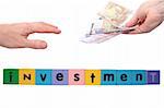 toy letters that spell house investment with cash in hands against a white background with clipping path