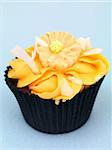 A freshly baked cup cake with orange frosting