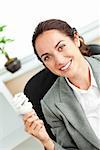 Bright hispanic businesswoman holding a light bulb sitting at her desk in her office