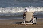 old lady sitting in a chair on the beach in Biarritz, the Basque Country, France