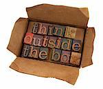 think outside the box concept, words  in vintage letterpress type  in open cardboard box, isolated on white