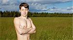 Naked young man on a background of green field