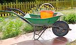 gardener green wheel barrow with orange pail cube tools