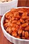 White canned beans in a white ceramic dish with red sauce.