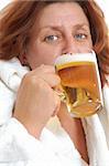 Mature woman drinking beer in sauna. Isolated over white.