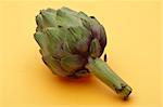 Fresh Green Artichoke on Yellow Background Healthy Eating Image.