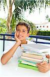 boy student teenager happy thinking with books stacked outdoors