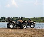 A pair of quad bikes on sandy riverside