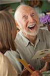 Senior man at home reading greeting card with wife