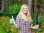 Young beautiful woman gardening and trimming the hedge