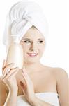 Young beautiful woman with healthy pure skin and white towel on her head holding moisturizing body lotion