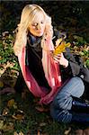 warm and fashion portrait of blond model sitting on the grass in a sunny winter day with hair style