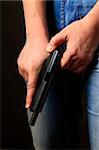 Black pistol in a man's hand on dark background