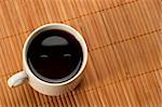 Little white espresso coffee cup on a bamboo mat (upprer view)