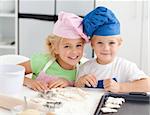 Portrait of two adorable children baking in the kitchen at home
