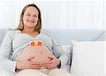 Happy future mom having cubes on her belly sitting on a bed