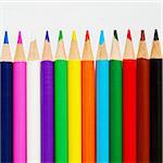 Color pencils in a row photographed on rough white paper