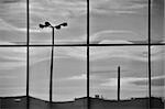 Overcast sky and street lights mirrored on the glass windows of a modern office building. Architectural detail.