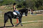 young teenager and her black horse in a training of jumping competition