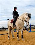 young teenager and her white black horse in a training of jumping competition