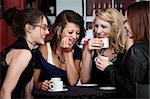 A foursome of pretty girls laughing in a cafe