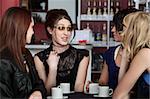 Four cute young ladies gossip at a restaurant over coffee