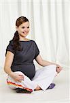 Young pregnant woman doing yoga exercises on sitting on the floor