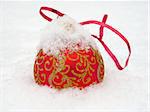 Red Christmas ball lies in the snow