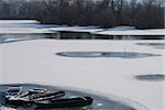 Winter landscape. Small frozen river and boats  on ice