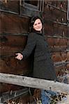 Beautiful brunette female leaning against a barn wall