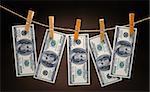 US Dollars Hanging on Rope with Clothespins on dark background