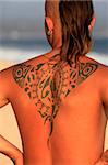 The young man with a beautiful tattoo on a coast of ocean