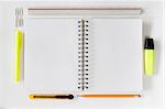 Open notebook with various stationeries or office supplies, white blank pages