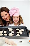 Happy mother and daughter holding a plate with biscuits in the kitchen