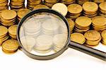 Stack of coins and magnifying glass on the white