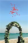 Beach wedding with red balloons and boat