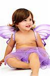 little girl with purple angle wings sitting in studio and smiling