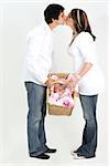 couple holding new baby in basket and kissing