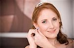 red head sexy beautiful bride inserting her earrings in whilst smiling
