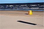 big yellow dustbin in background of blue still sea and sky