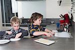 Two boys doing the dishes in a modern kitchen.