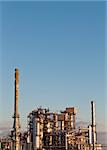 A petrochemical refinery plant in the evening with pipes and cooling towers.