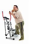 Overweight man eating a large hamburger standing by an exercising device - fittness fail concept isolated
