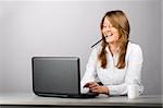 business woman is sitting in the office with laptop and smiling with pencil in mouth