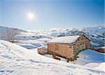 Remote mountain hut on a slope in the sunlight