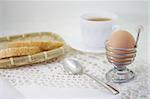 isolated egg in retro metallic spiral eggcup, metallic teaspoon and slice of bread at the white background