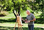 Senior man painting in the park