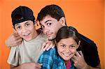 Teen holding and playing with brother and sister on an orange background