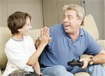 Uncle giving his nephew a high five as they play video games.  Could also be father and son.